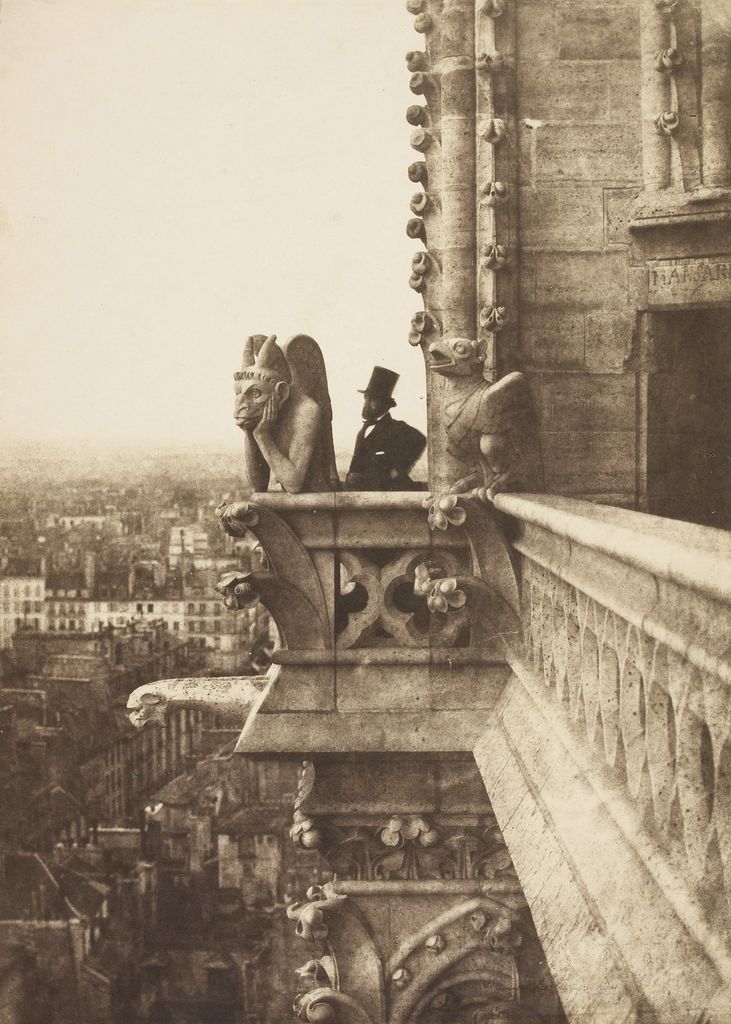 An 1853 sepia photograph shows a horned stone chimera leaning over a high cathedral balcony beside a man in a top hat, with Paris fading into the distance below.