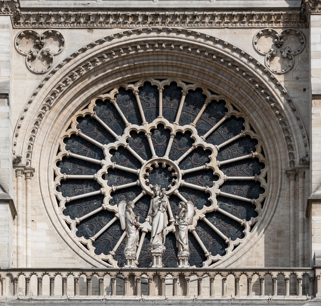 A close view of Notre-Dame's west rose shows radial stone tracery, dark patterned glass, nested arches, quatrefoils and three standing figures on the gallery below.