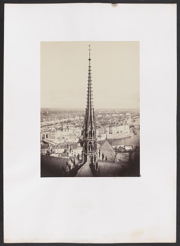 A mounted 1860 photograph shows Notre-Dame's slender crossing spire above lead roofs and a ring of statues, with the River Seine and dense Paris cityscape stretching behind it.
