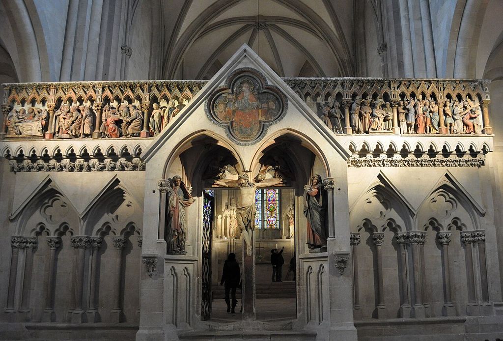 Carved reliefs and figures surround a double pointed entrance through a stone choir screen.