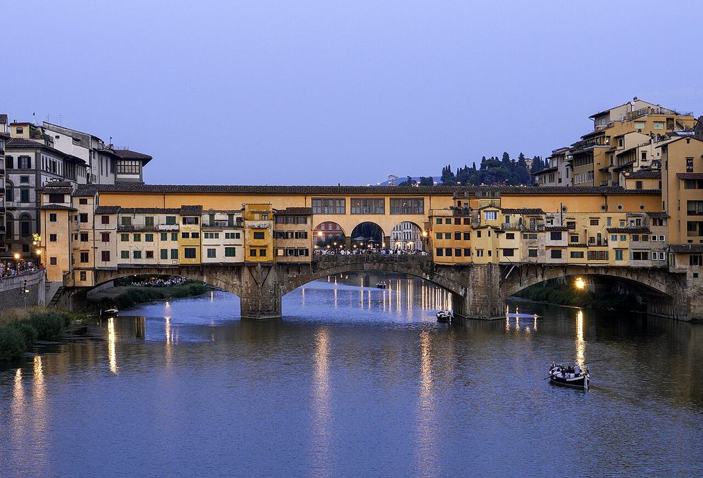 A continuous line of shops and rooms stands above a three-arched river bridge.