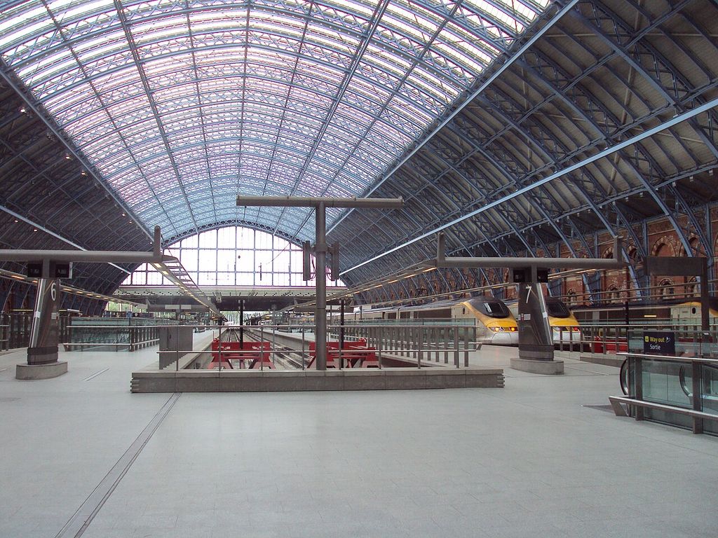 Railway platforms and tracks extend under a wide glazed metal roof.