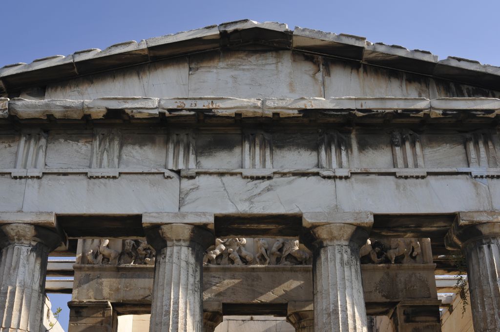 Fluted upper shafts and broad capitals carry horizontal stone members below a triglyph-and-metope frieze.