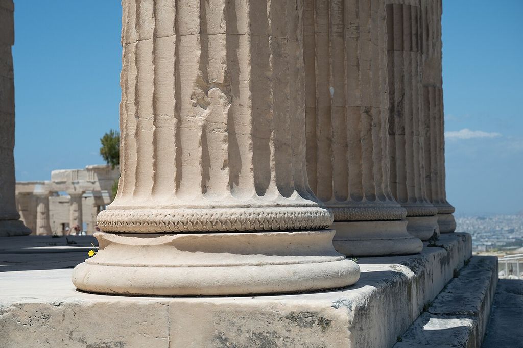 Rounded moulded bases with carved bands support fluted stone shafts on a stepped platform.