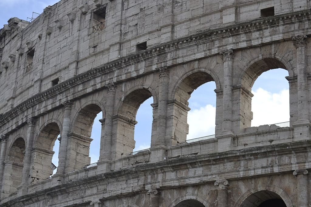 Rounded attached columns rise between large stone arches beneath flatter pilasters on the upper wall.