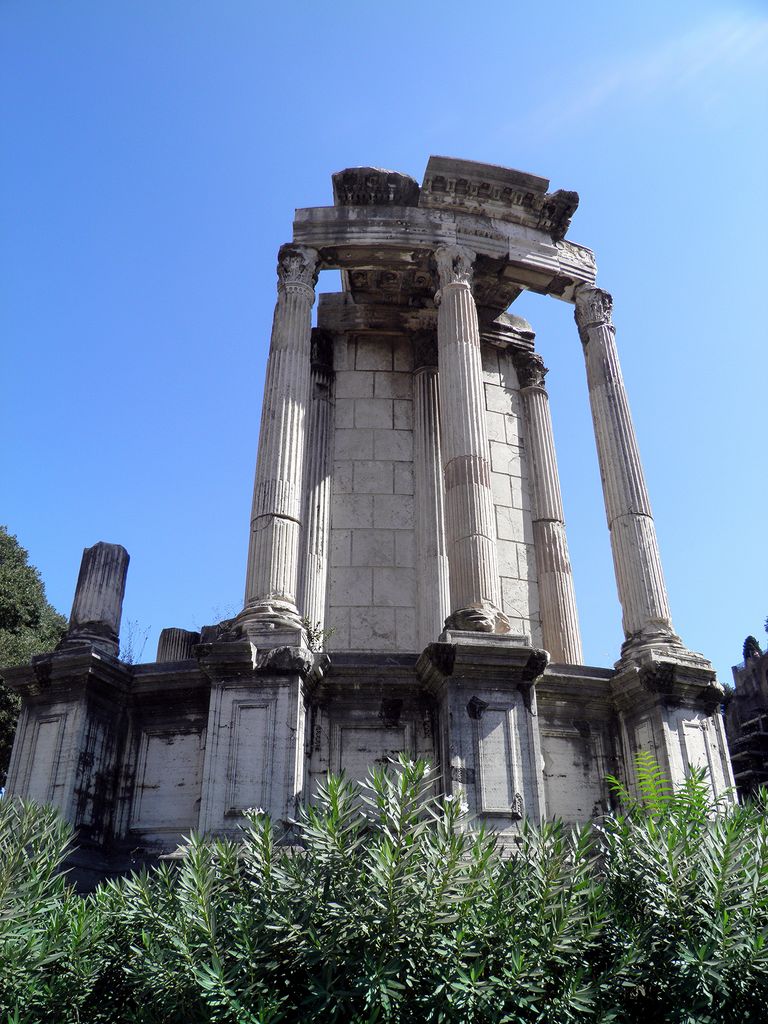 A partial ring of fluted Corinthian columns and curved entablature stands on a round marble-clad podium.
