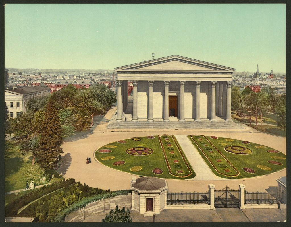 A monumental rectangular building with Corinthian columns on all sides stands above broad steps and formal gardens in a historic colour print.