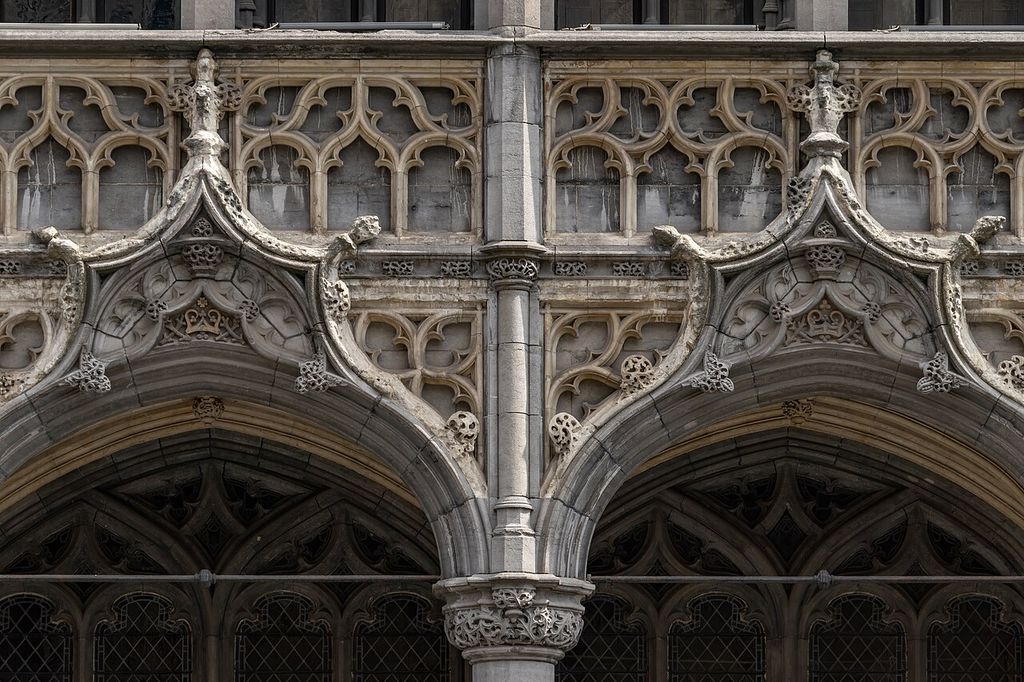 Close-up view showing two pointed arches of the ground-floor loggia, highlighted by intricate ogee gables, decorative crockets, and a blind tracery balustrade above