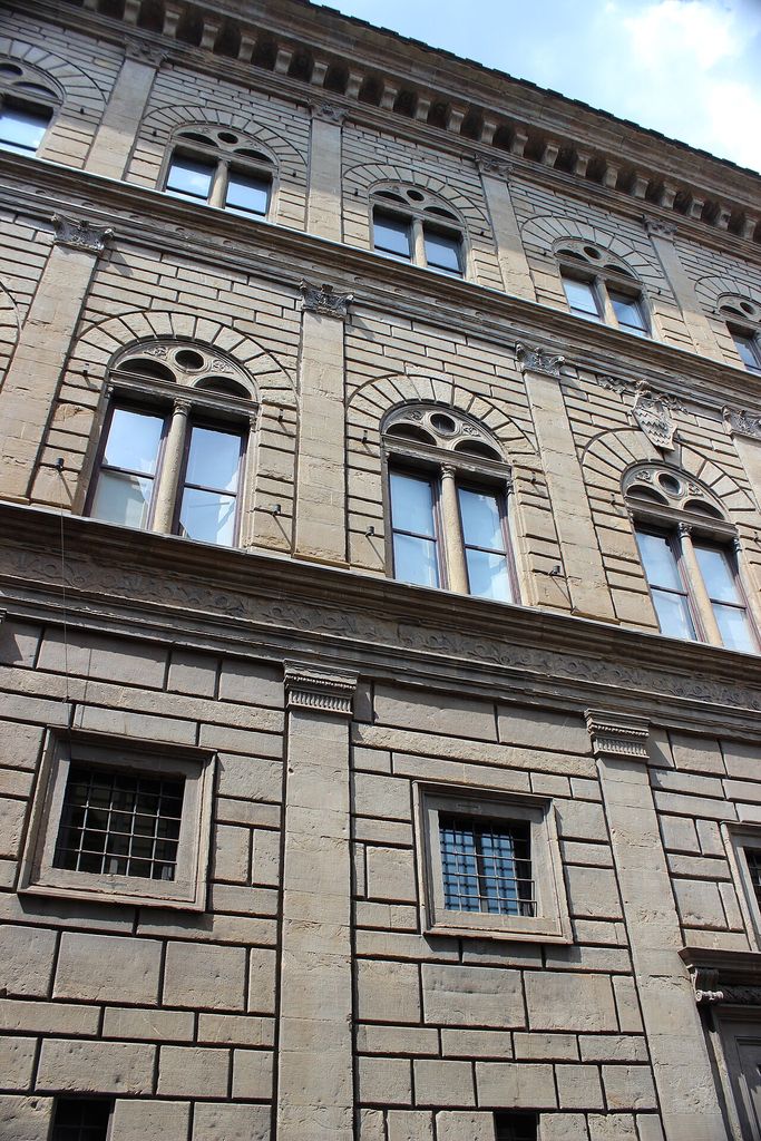 Articulated stone façade with arched windows and horizontal courses.