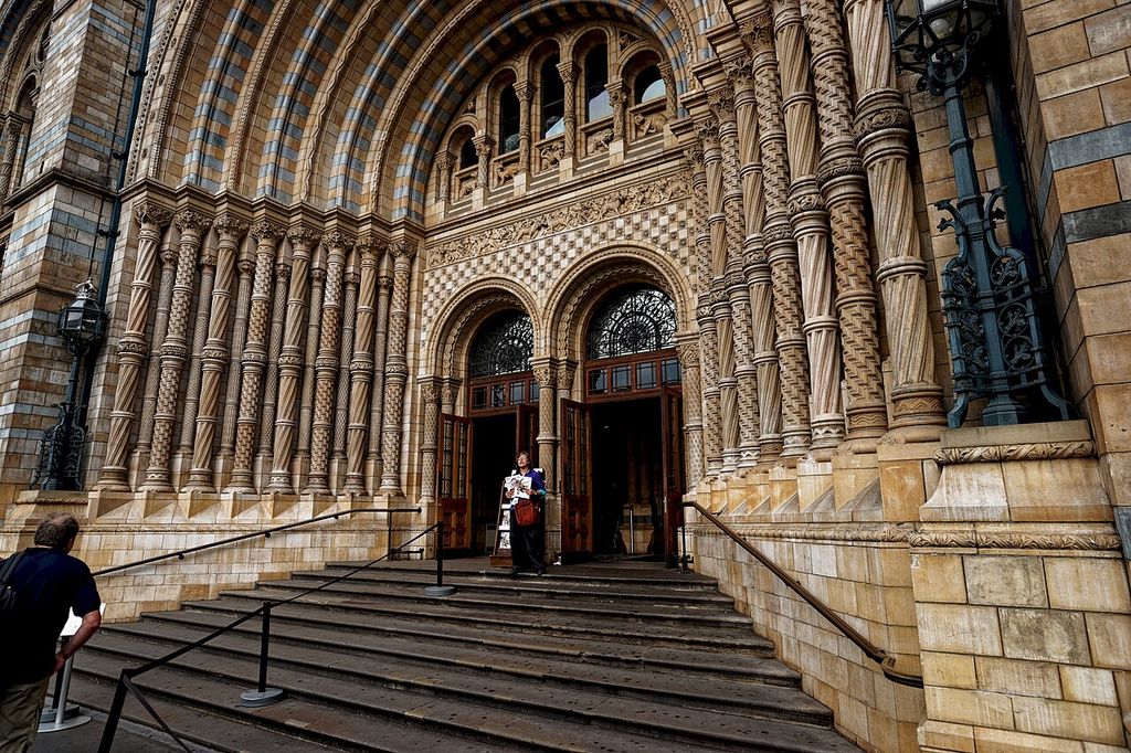 Deep striped arches, carved terracotta columns, patterned panels, iron grilles, timber doors and broad stone steps frame a museum entrance.