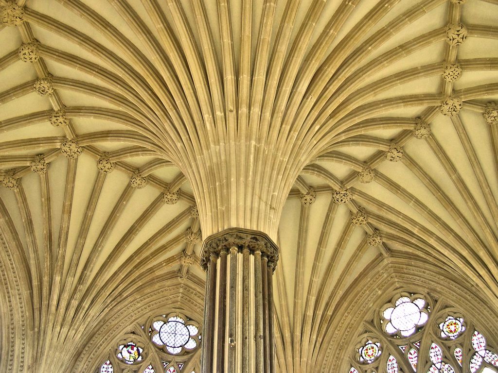 Many moulded stone ribs spread from a central clustered pier toward carved bosses across a pale ceiling.