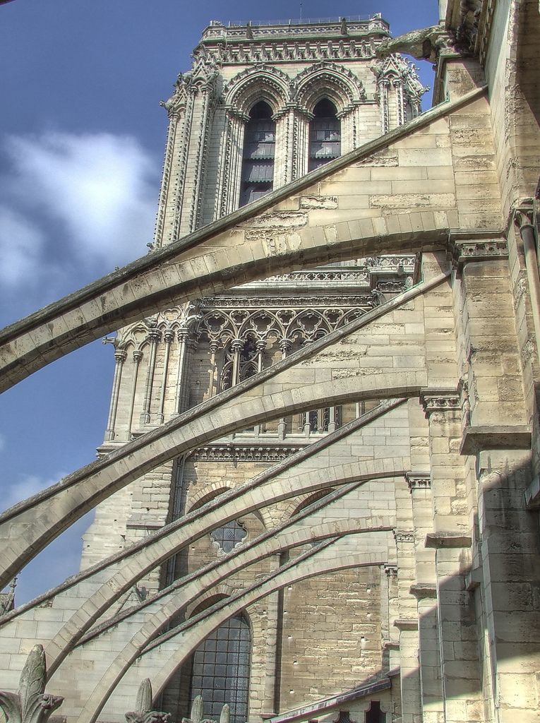 A row of solid stone arches slopes upward to the church wall beneath projecting coping.