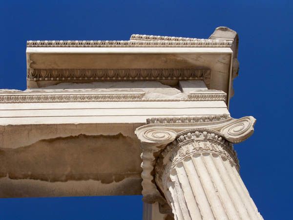 Two large spiral volutes top a fluted marble shaft beneath carved horizontal bands.