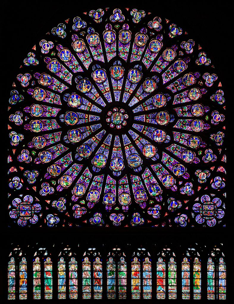 A brilliant circular stained-glass rose of concentric figures glows above a row of narrow lancets against a dark interior.