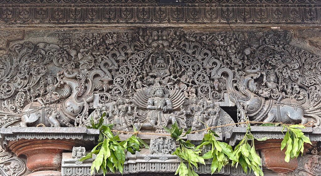 The exquisitely carved Makara Torana above the eastern entrance showcases Narasimha killing the demon king Hiranyakashipu, surrounded by the Dashavatars of Vishnu, with Garuda in a supplicating posture below, showing torana Indian temple.