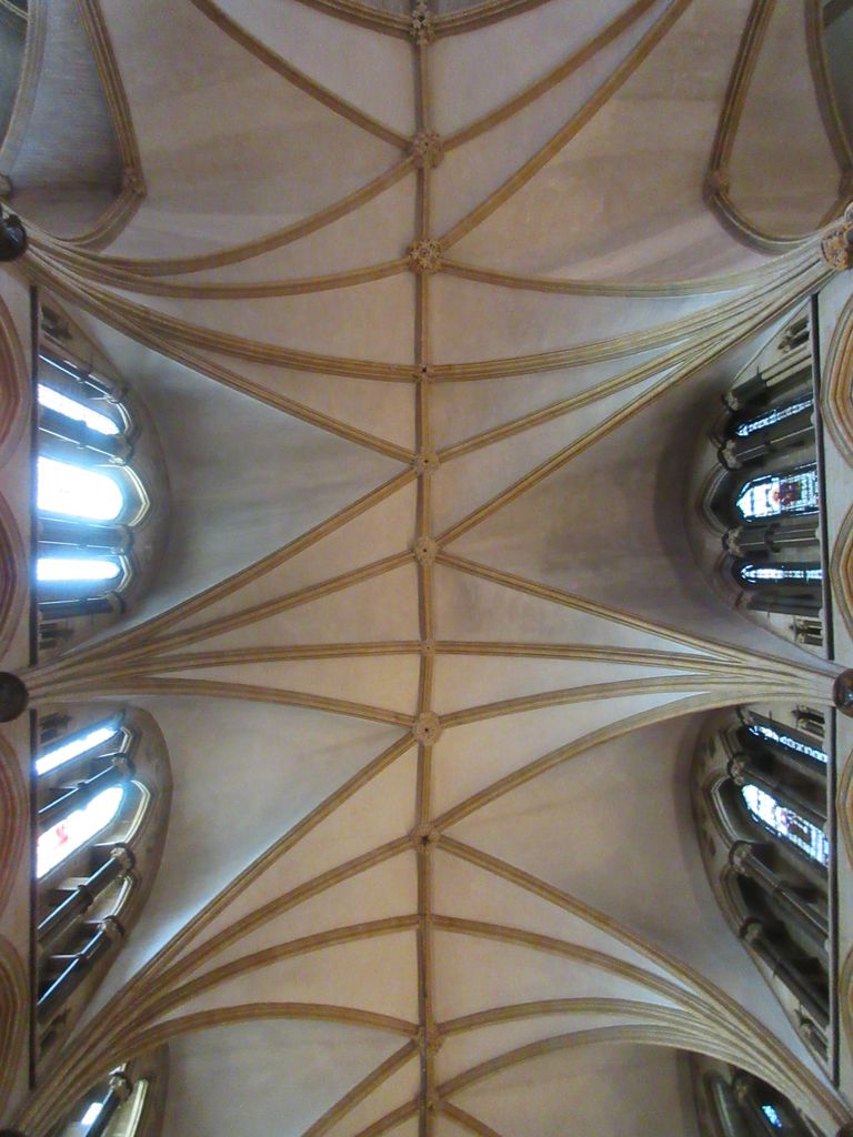Ribs spread across pale vault surfaces and meet a central ridge at staggered junctions, with clerestory windows at both sides.