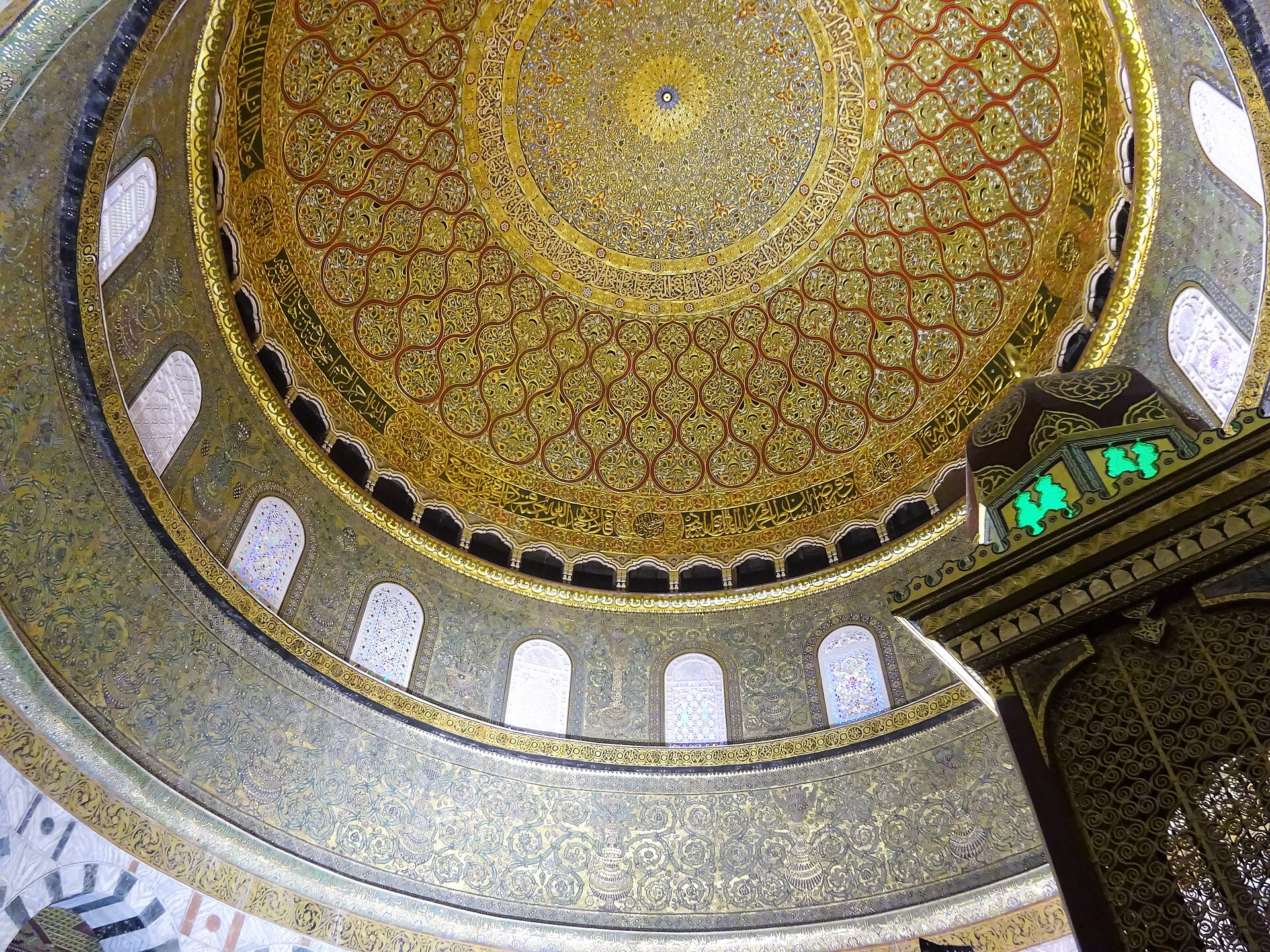 Looking up into the richly patterned inner dome and surrounding windowed drum of the Dome of the Rock.