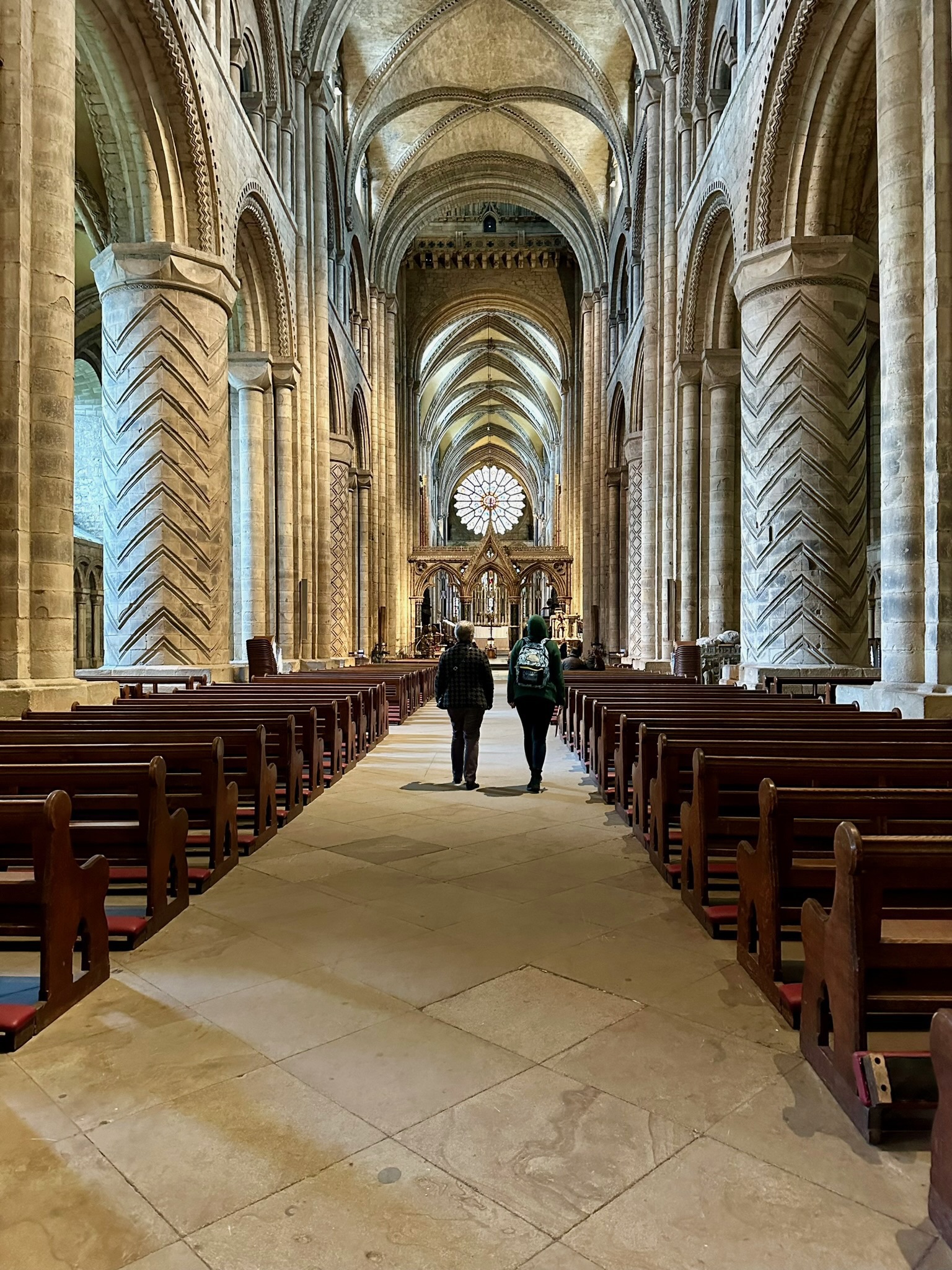 Durham Cathedral's central nave seen eastward between huge patterned cylindrical piers and compound supports beneath galleries, clerestory and ribbed vault.