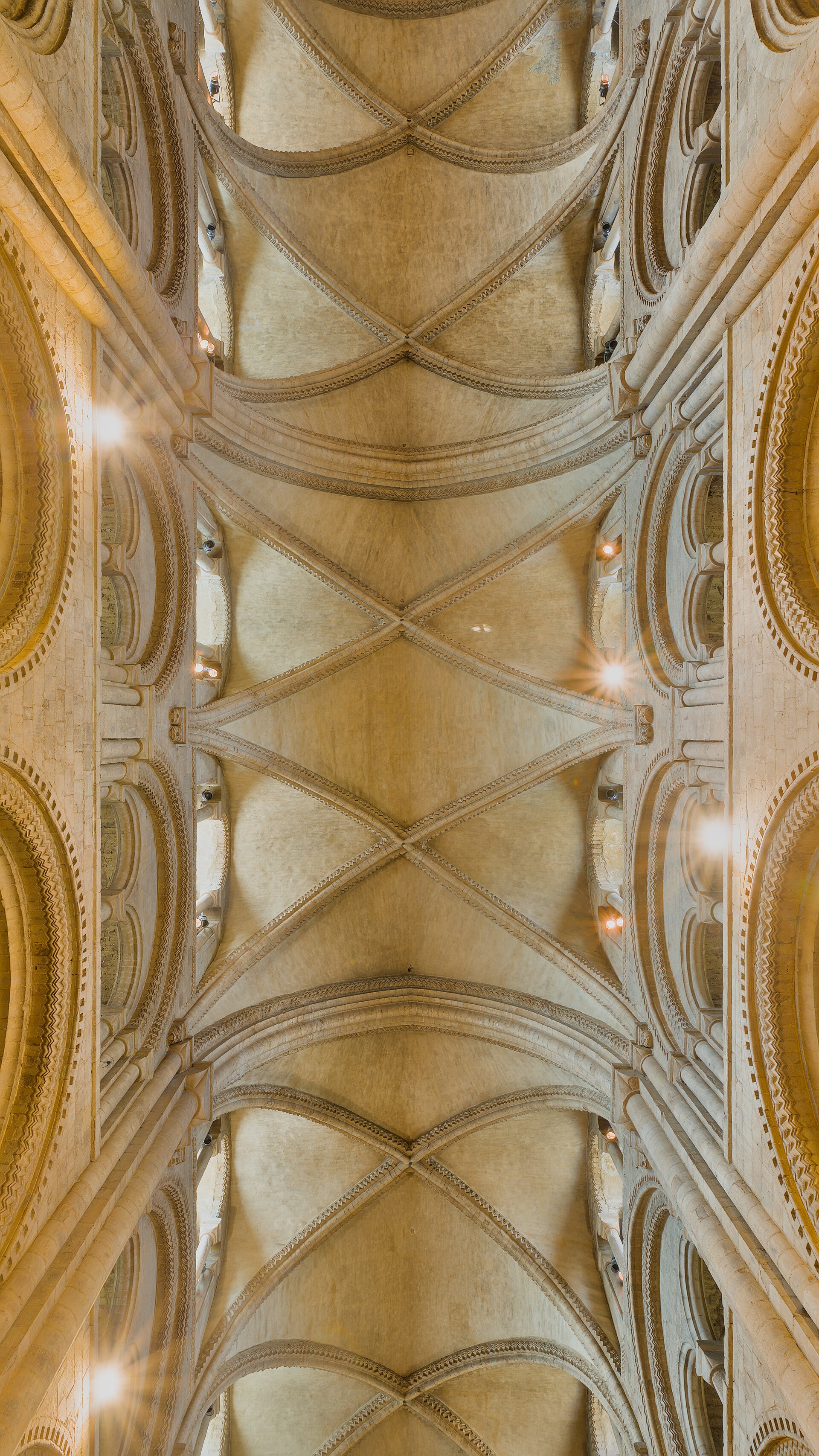 Upward view of Durham Cathedral's stone vault, where diagonal ribs cross between transverse arches and masonry webs.