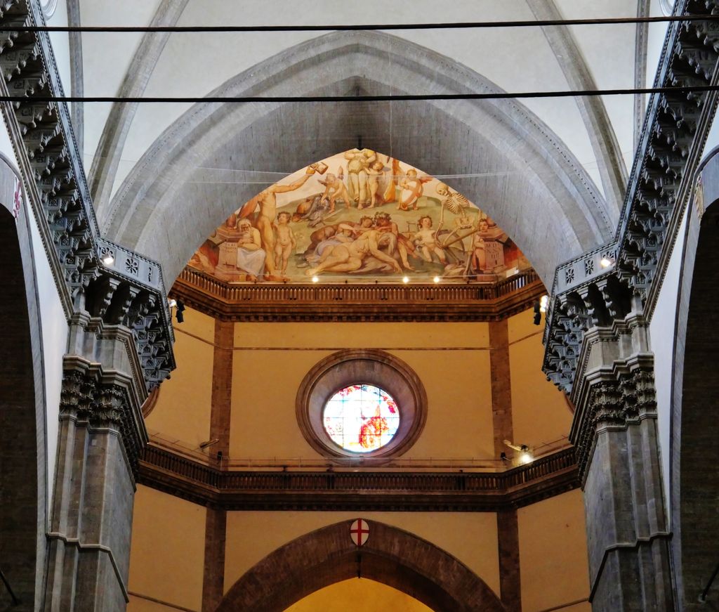 A huge pointed stone arch spans a pale cathedral interior above dark-edged piers, a circular stained-glass window and a painted lunette.