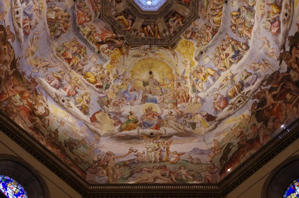 A vast painted Last Judgment covers curving sections inside a cathedral dome and rises toward an octagonal lantern opening.