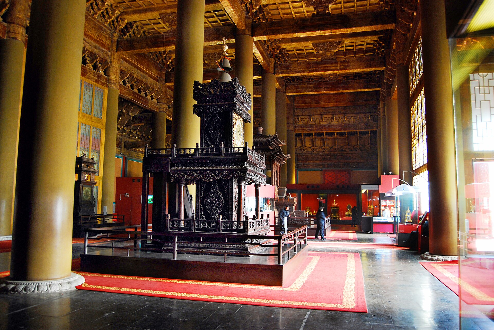Columned timber interior of the former Fengxian Hall, with large displayed clocks and museum cases.