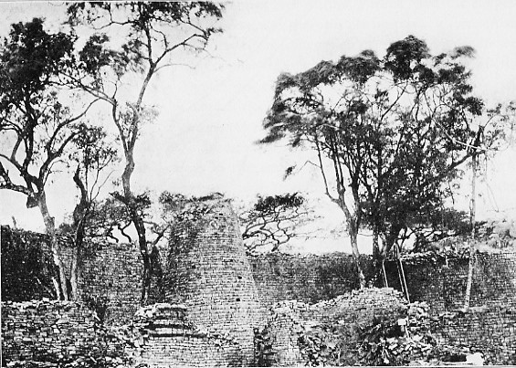 Black-and-white early-twentieth-century view across low interior walls to the conical tower and higher outer masonry.