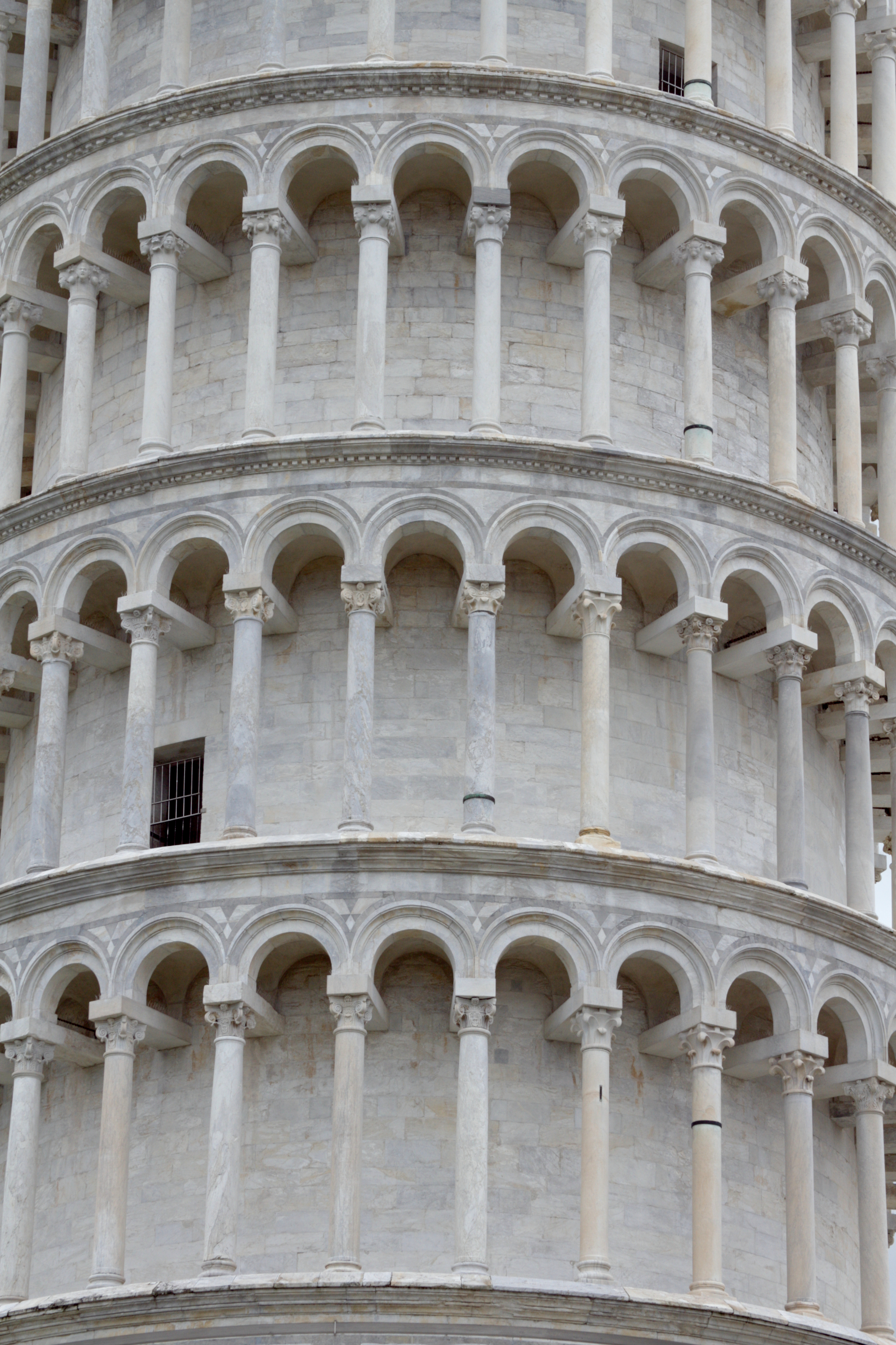 Close view of stacked open loggias on the Leaning Tower of Pisa, with columns, round arches and projecting cornices.
