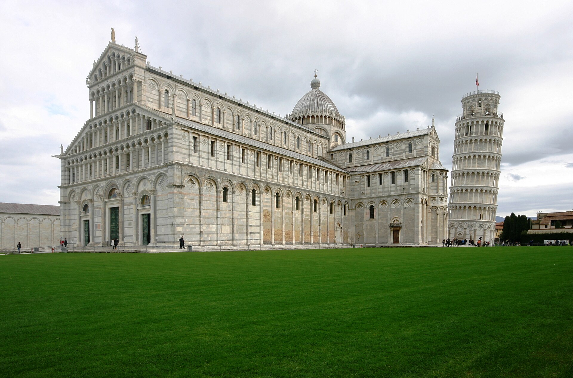 Pisa Cathedral and the Leaning Tower seen together across the lawn of Piazza del Duomo.
