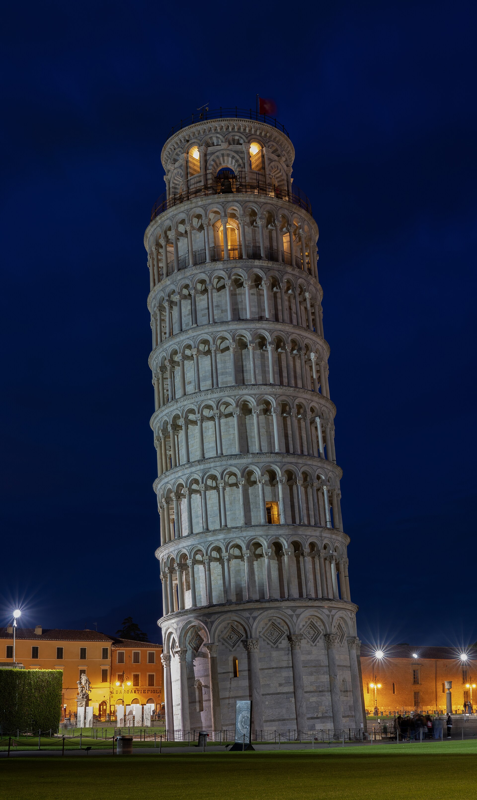 The Leaning Tower of Pisa illuminated at night, showing the full cylinder and open belfry against a dark sky.