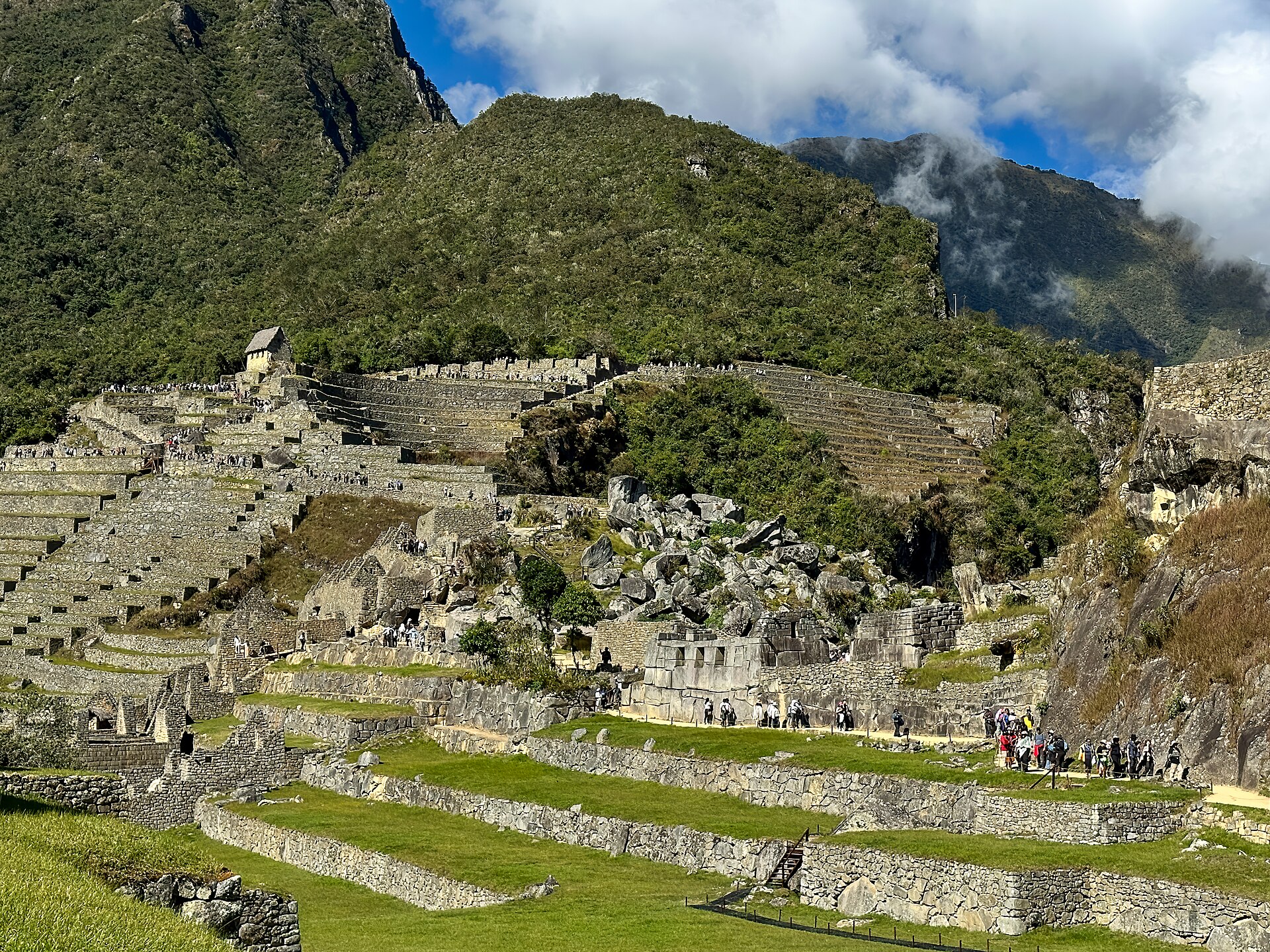Main-plaza view over rough granite quarry rocks, urban masonry and stepped terraces towards mountain slopes.
