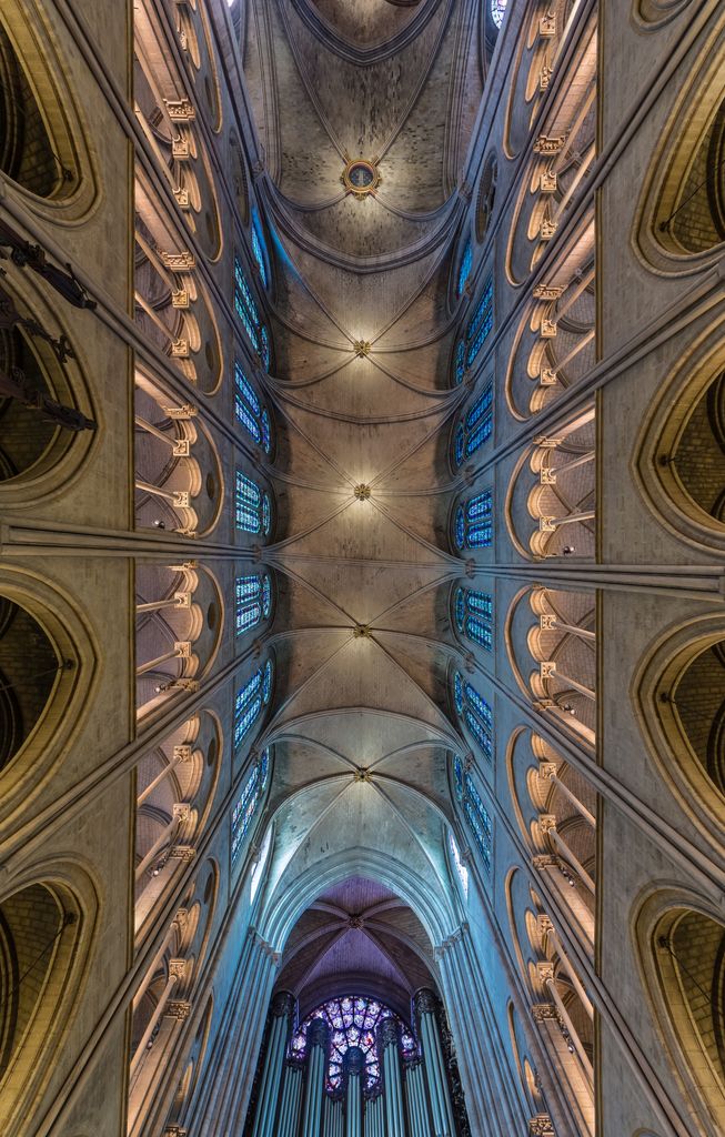 Looking steeply upward along Notre-Dame's nave, repeated stone ribs divide high vaults above two tiers of arcades and rows of blue-lit clerestory windows.