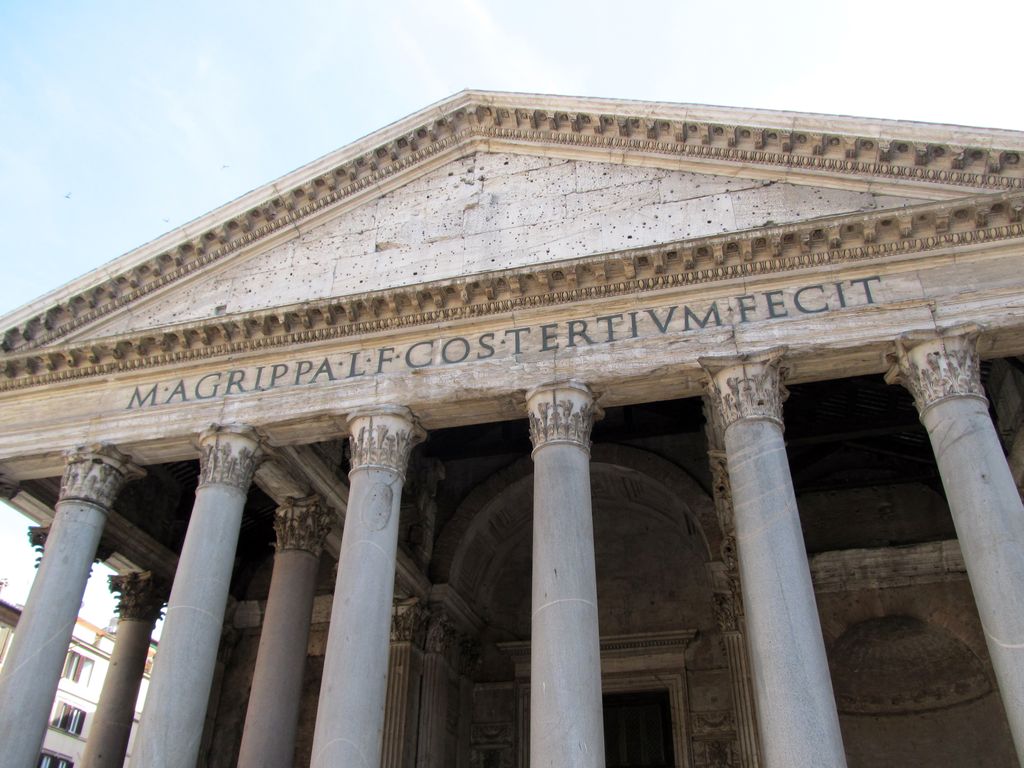 A low-angle view of the Pantheon's triangular pediment and Corinthian portico shows the long Latin inscription naming Marcus Agrippa across the stone entablature.