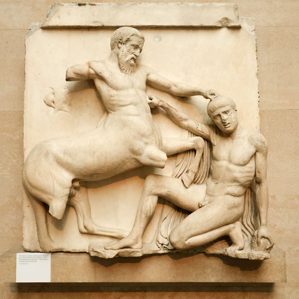A square marble relief mounted on a museum wall shows a centaur trampling and seizing a crouching nude man, with several limbs and frame sections missing.