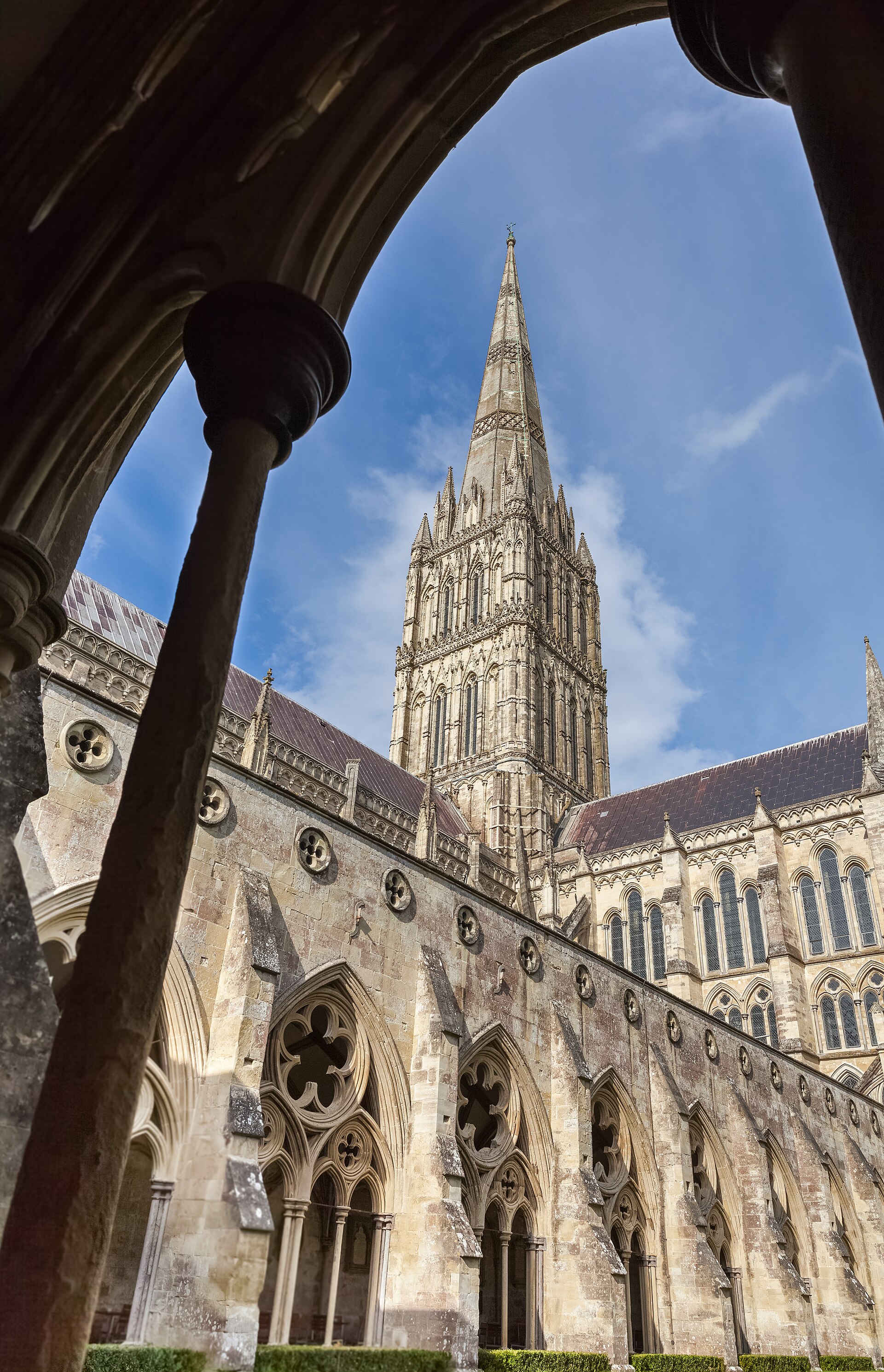 Salisbury Cathedral cloister walk with repeating paired openings, dark Purbeck shafts, plate tracery and a ribbed vault beside the sunlit garth.