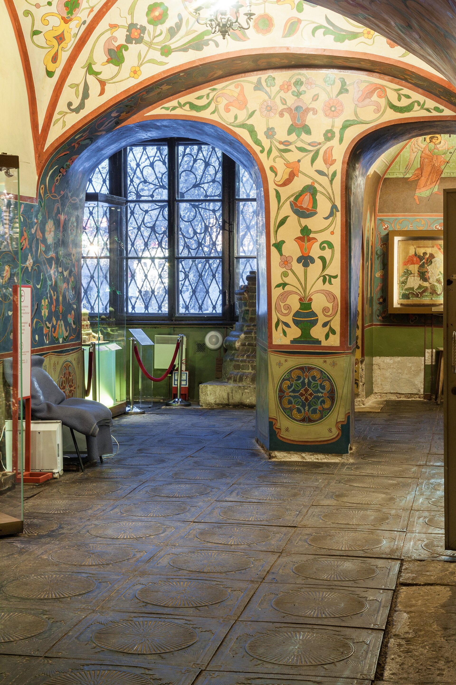 Present museum room in the cathedral’s lower podklet with vaulted arches, decorated walls and stone floor.