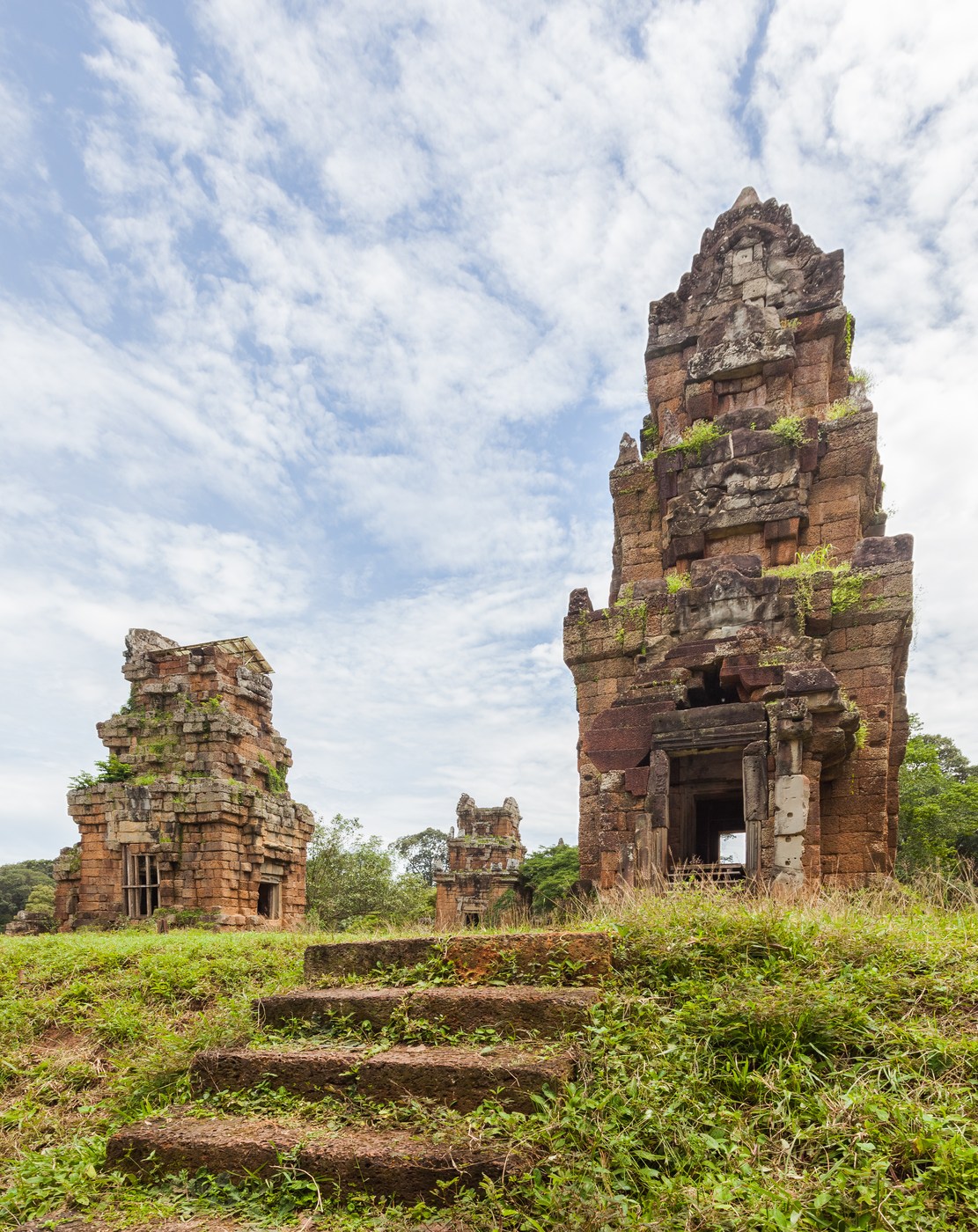 Prasat Suor Prat stone towers with stepped profiles, door openings and vegetation around their bases.