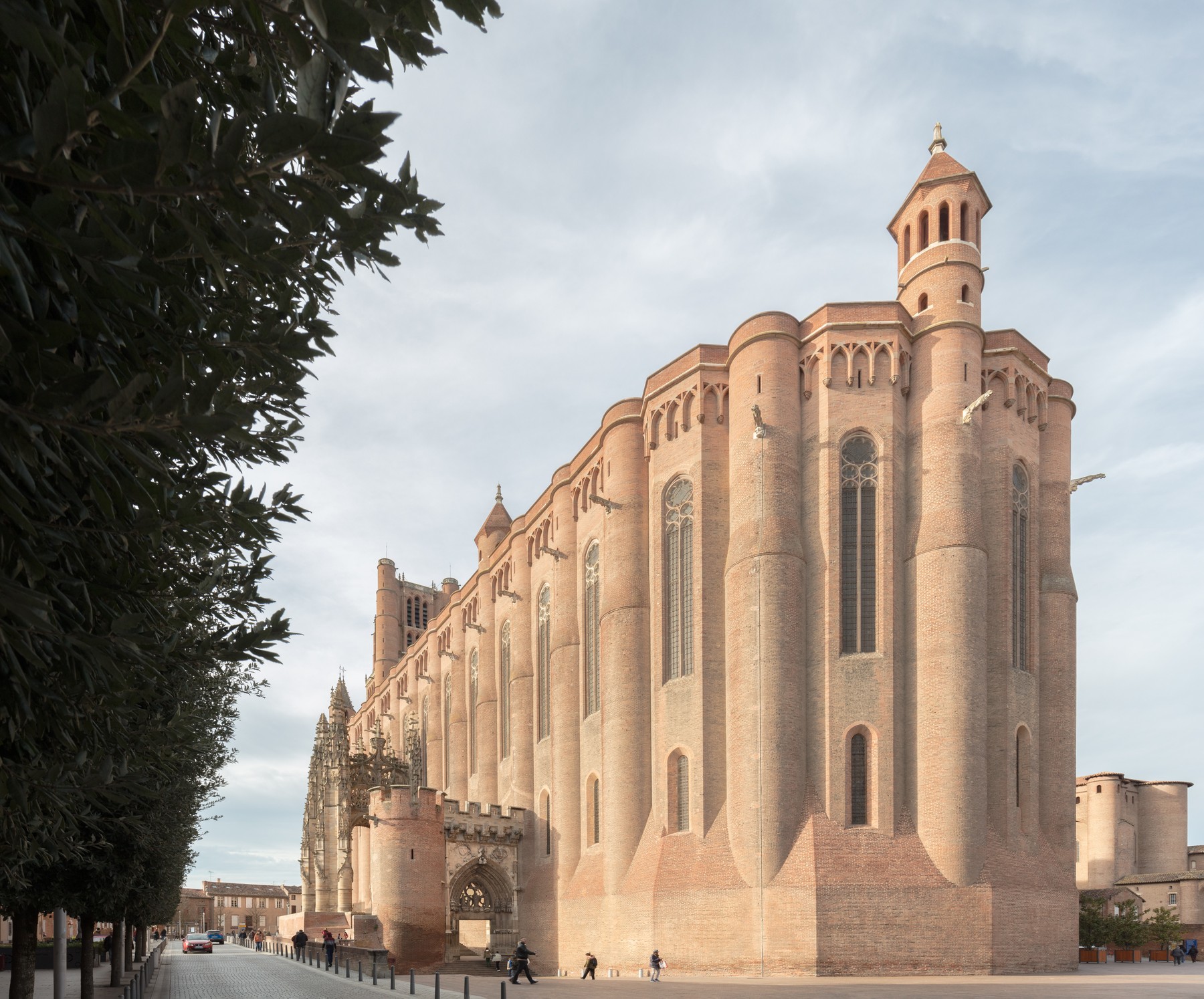 Large brick cathedral exterior with rounded projecting bays, tall windows and a contrasting ornate stone porch.