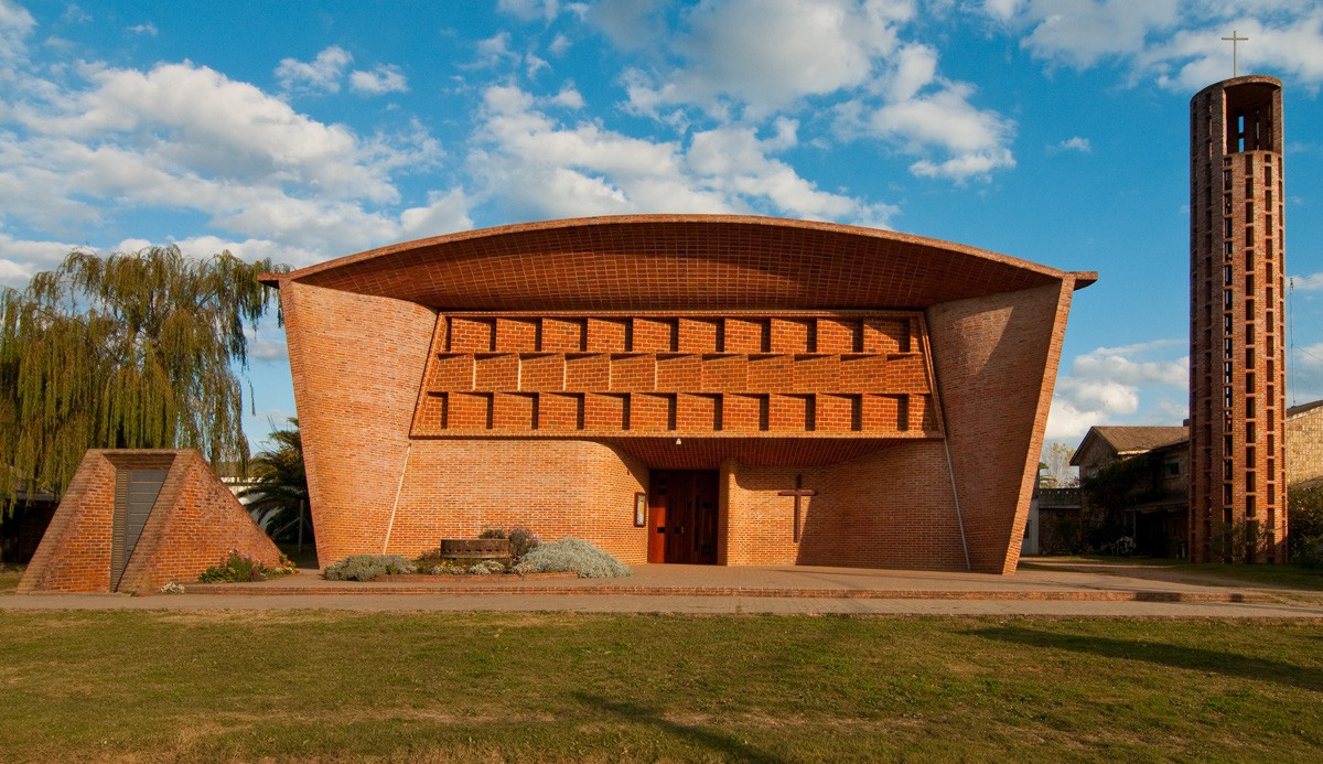 Brick church with a curved roof and façade profile, central entrances and a tall cylindrical openwork tower.