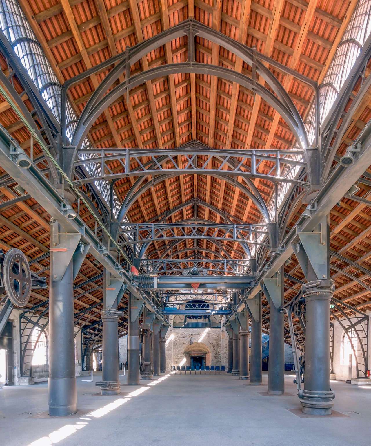 Tall columns and pointed metal arches frame the central aisle of Sayner’s casting hall, with lower side aisles and lifting equipment.