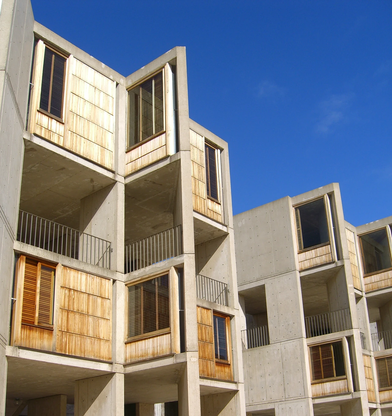 Repeated concrete masses frame tall teak-panelled openings and recessed balconies at the Salk Institute.