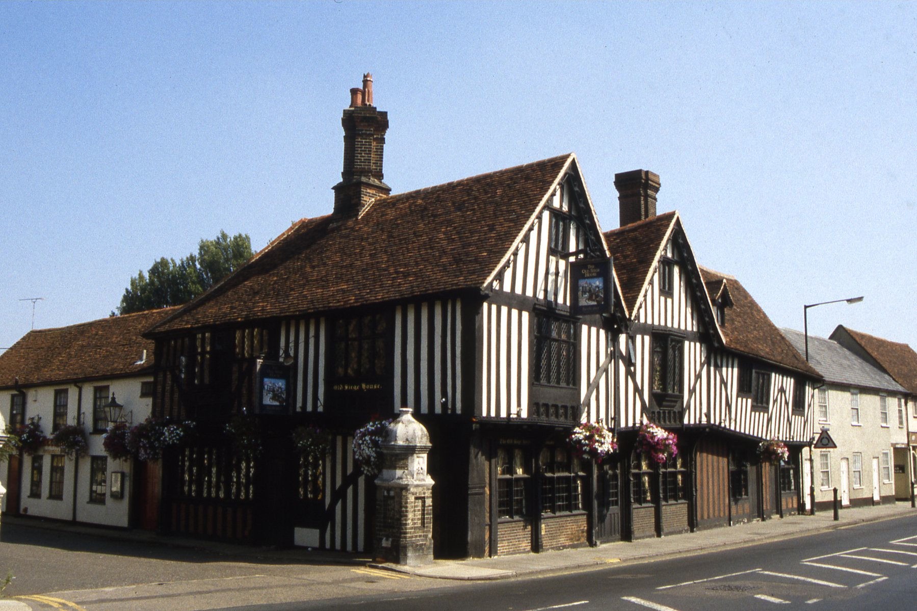 Colchester's Siege House along the street, with two prominent gables, dense vertical timberwork, pale panels and ground-level entrances.