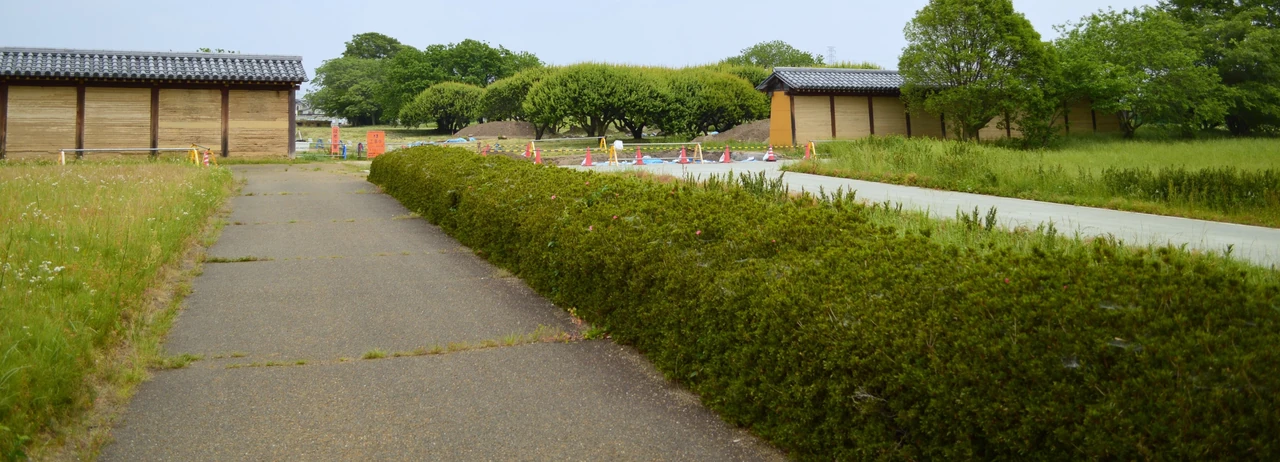 Modern reconstructed tiled earth enclosure and timber posts flanking the south-gate site at Kōzuke Kokubunji.