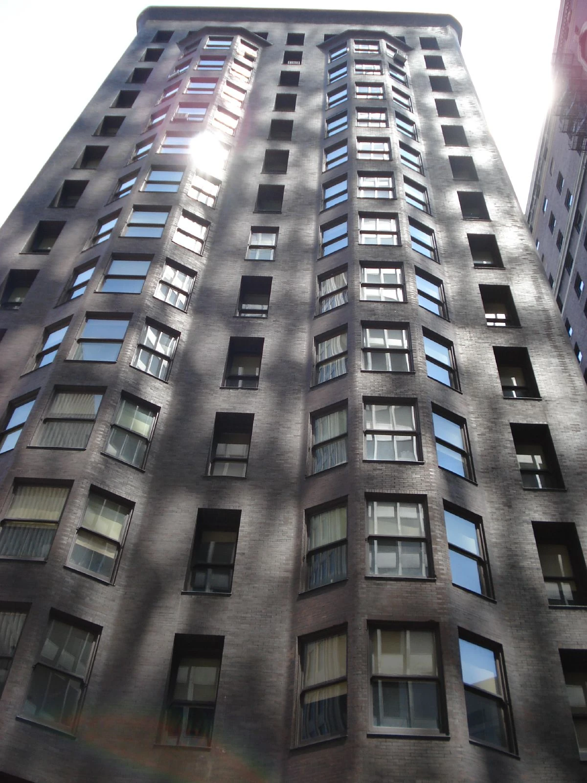 Projecting window bays rise through the Monadnock Building’s dark brick exterior in an upward street view.