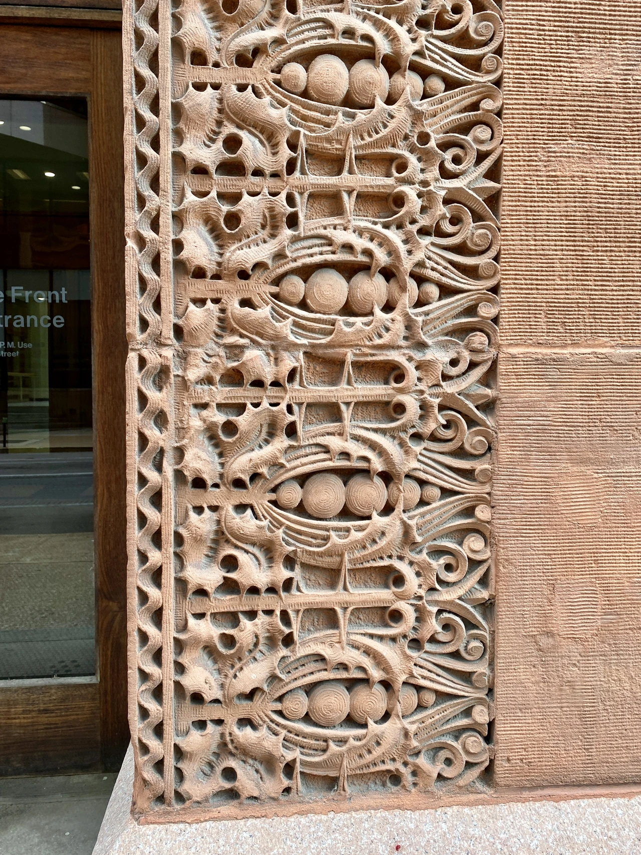 Leaf-like and geometric terracotta mouldings frame a timber doorway beside red brick at the Wainwright Building.