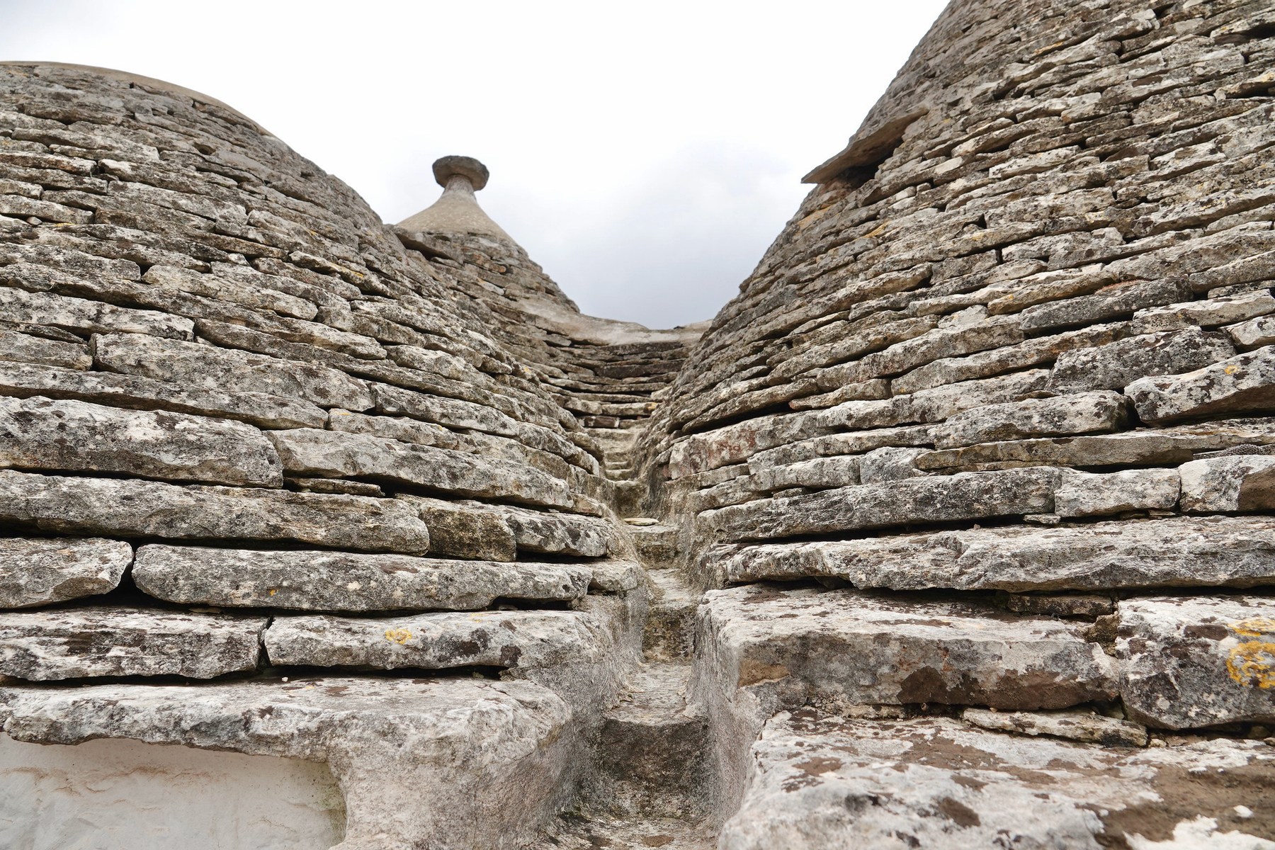 Thin stone roof courses on two neighbouring trulli at Alberobello, meeting at a recessed junction.