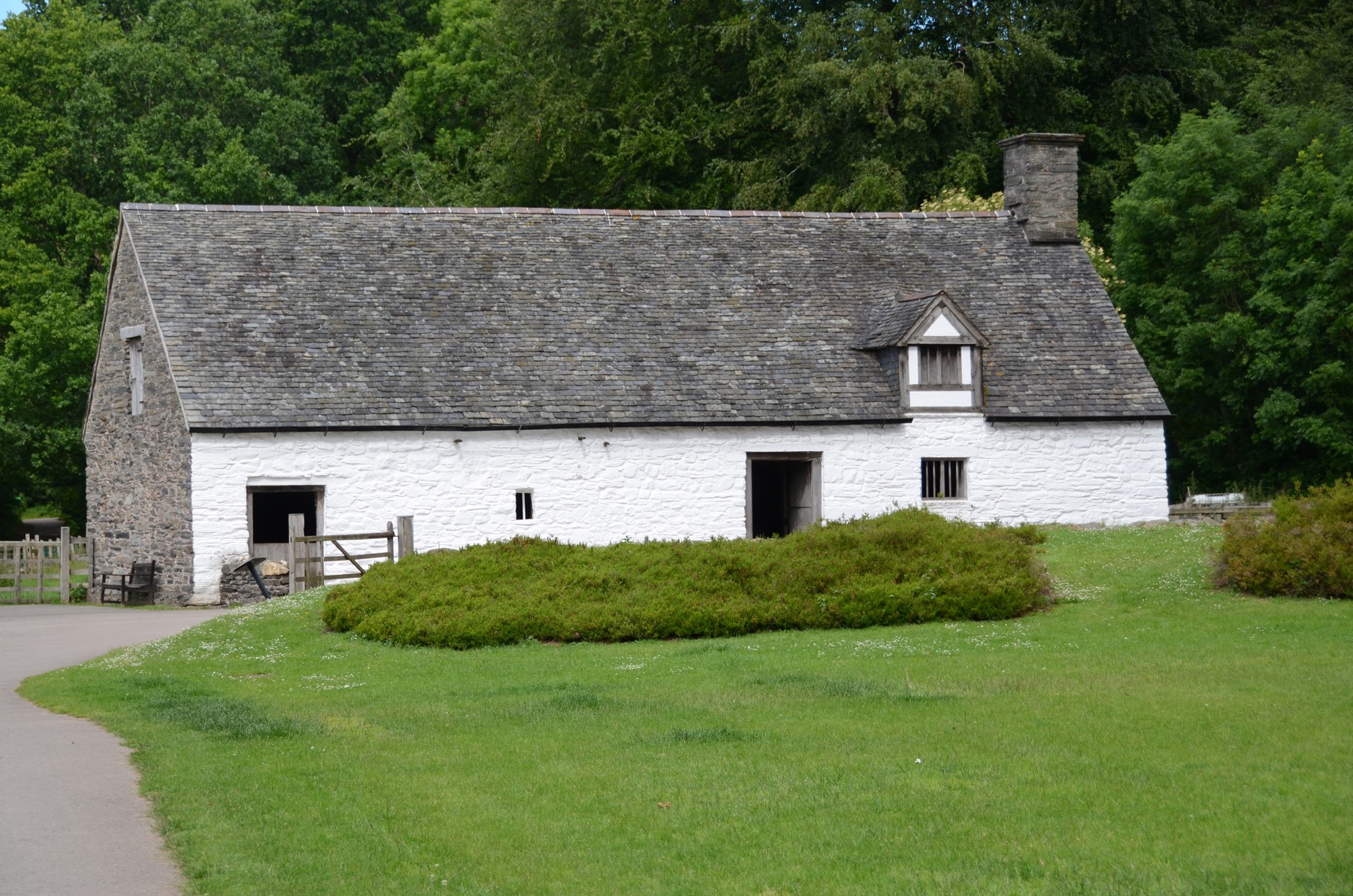 Cilewent farmhouse with a rough stone end wall, white limewashed long wall and low roof.