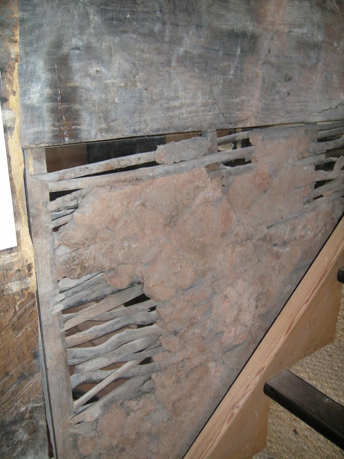 A tall Boscobel dairy wall panel behind glazing, with horizontal rods exposed beneath areas of earth facing.