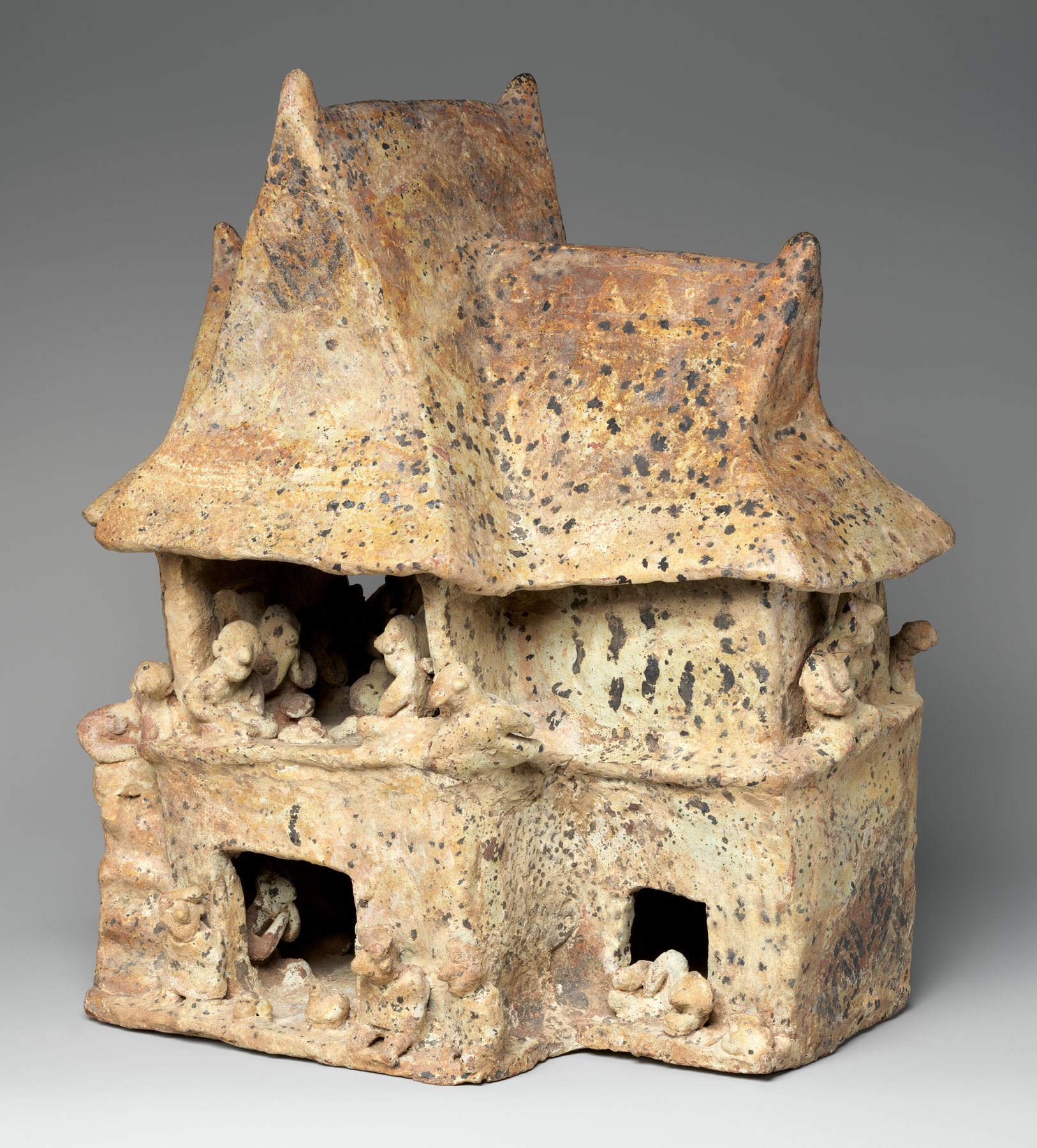 Nayarit ceramic house with two meeting hipped roof forms and small people visible in upper and lower openings.