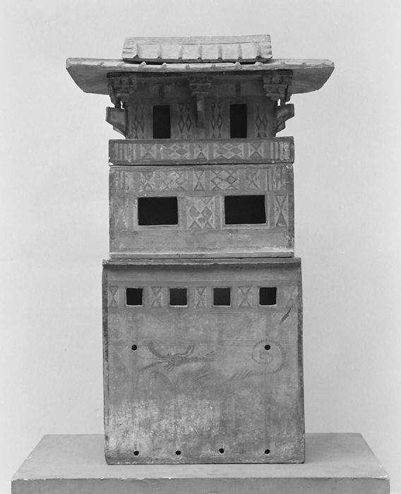 Front view of an Eastern Han earthenware tomb-house model with several openings, patterned bands and an overhanging roof.